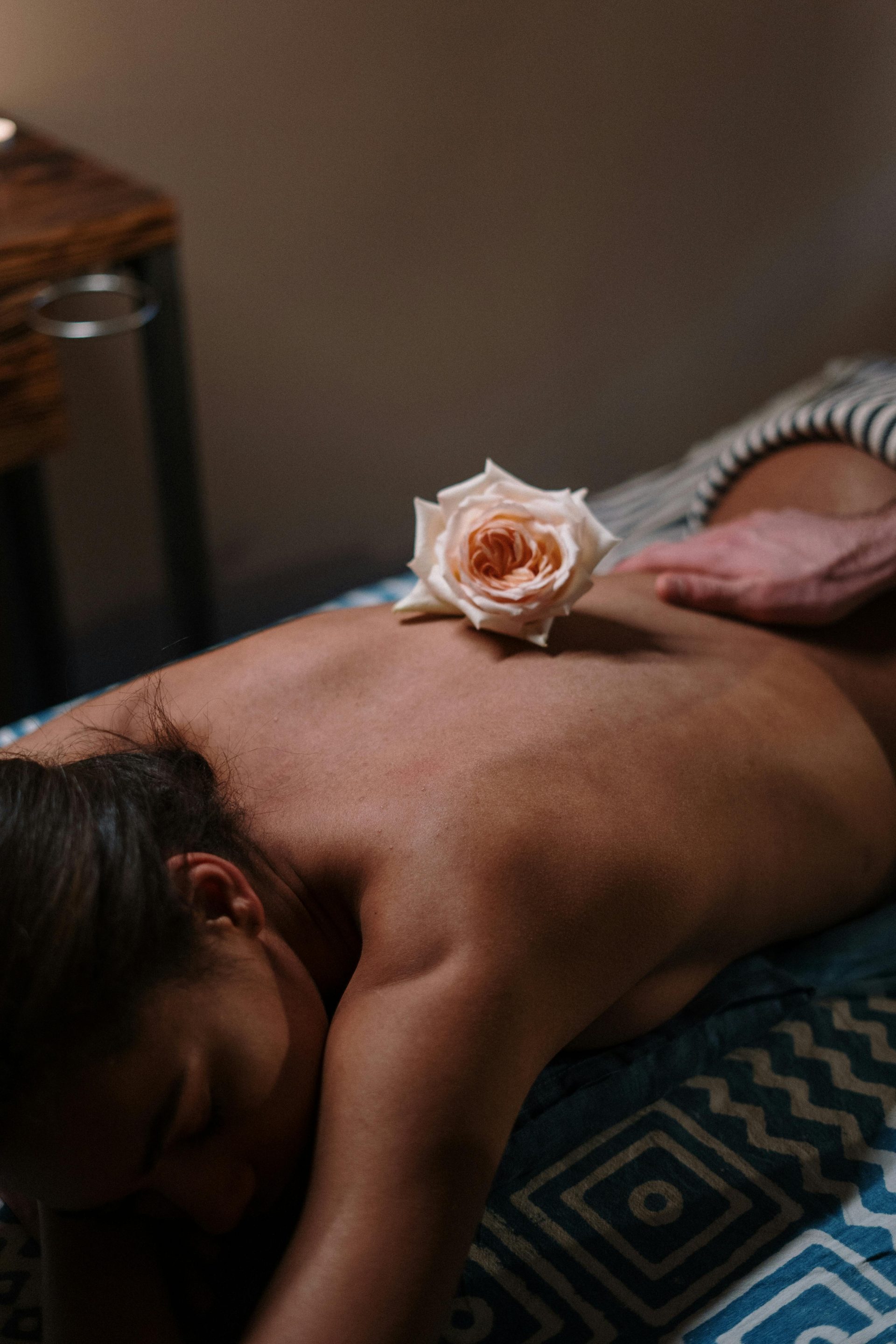 Soothing spa experience featuring a delicate rose on a woman's back promotes relaxation and wellness.